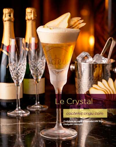 Cóctel Le Crystal presentado en copa lujosa con rodajas de pera sobre fondo oscuro desenfocado con botellas de champan, hielera y rodajas de pera. Cóctel Le Crystal presentado en copa lujosa con rodajas de pera sobre fondo oscuro desenfocado con botellas de champan, hielera y rodajas de pera.